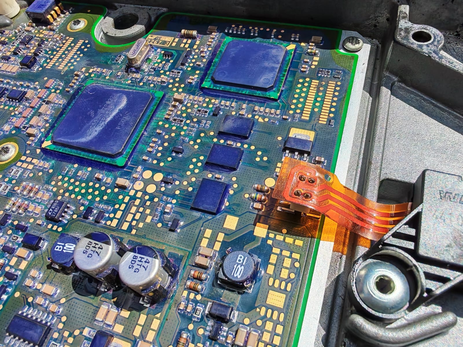 A truck control board on the bench, with processors, capacitors and a ribbon connector in daylight
